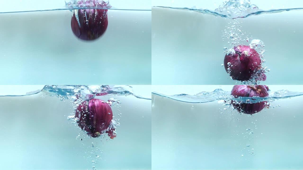 红洋葱掉入水箱中的慢动作镜头。