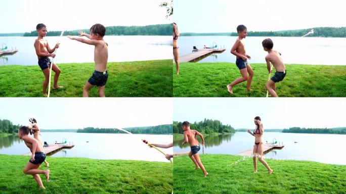 一个穿着泳裤的男孩把水倒在他的弟弟身上，他正在公园里的湖边草地上玩耍