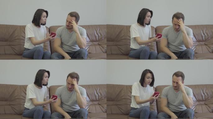 愤怒的女人对她悲伤的丈夫大喊大叫的肖像，向他展示了手机，上面写着他的情人在家里发来的信息。