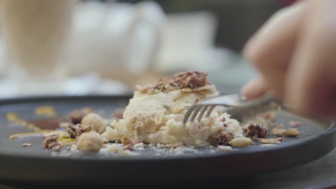食欲不振的餐厅游客切一块新鲜的土耳其奶油牛轧糖和坚果蛋糕。