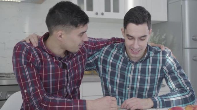 英俊的高加索双胞胎兄弟手牵在彼此的肩膀上微笑的肖像。两个成年男子看着地图计划假期。旅游，旅游，生活方