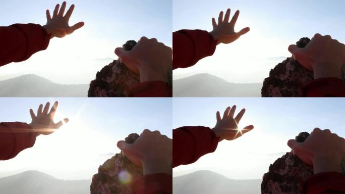 远足者的手在日出时越过山脉的细节