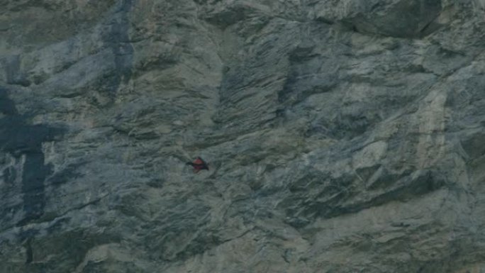 翼服飞行者跳跃，然后驶过岩石悬崖空中飞行