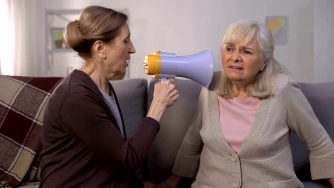 成熟的女人用扩音器对聋哑的老妇人说话，听力问题，笑话