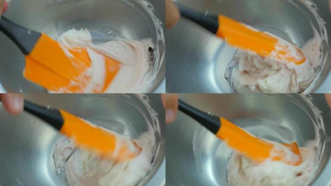 将浅粉色混合到黄油奶油中。特写。慢动作。