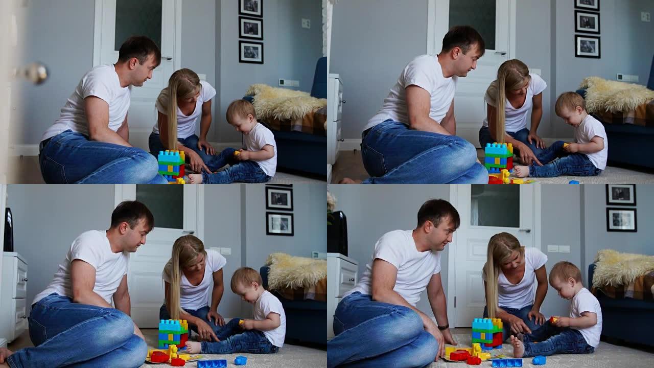 幸福的家庭爸爸妈妈和宝宝两年在明亮的客厅里玩塑料块。慢镜头拍摄幸福家庭