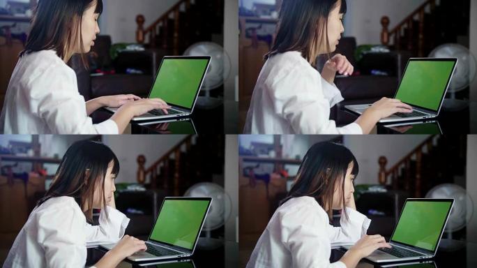 年轻女子在家工作，笔记本电脑上的绿屏