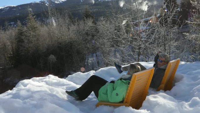 夫妇在雪堆中的椅子上放松