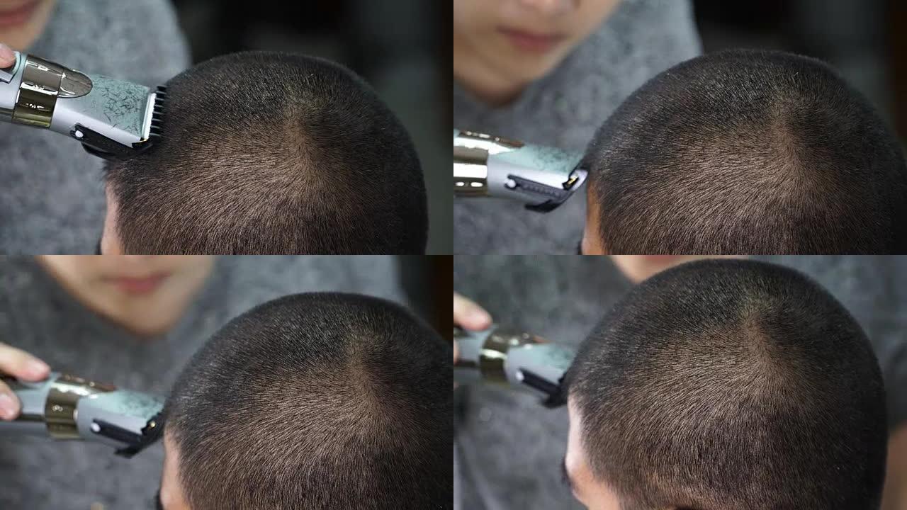 后视图: 年轻的理发师向泰国男人制造光头的手