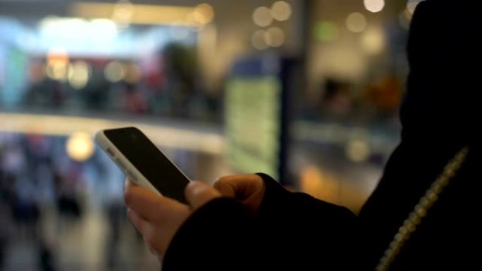 女性在智能手机上打字，站在购物中心，网上银行