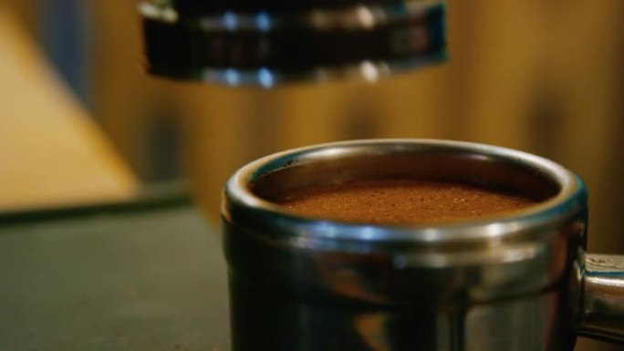咖啡师在咖啡店里做浓缩咖啡时在Portafilter中调平和夯实新鲜咖啡渣的特写镜头