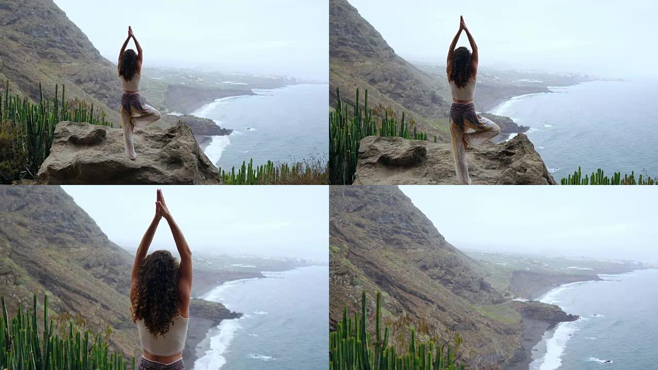 在瑜伽战士中冥想的女人在海洋，海滩和岩山上摆姿势。动机和鼓舞人心的适合和锻炼。大自然户外健康生活方式