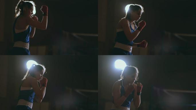 专业美丽的女拳击手穿着蓝色衣服，手腕上有红色绷带，在一个黑暗的大厅房间里慢动作地进行一场影子搏斗。s