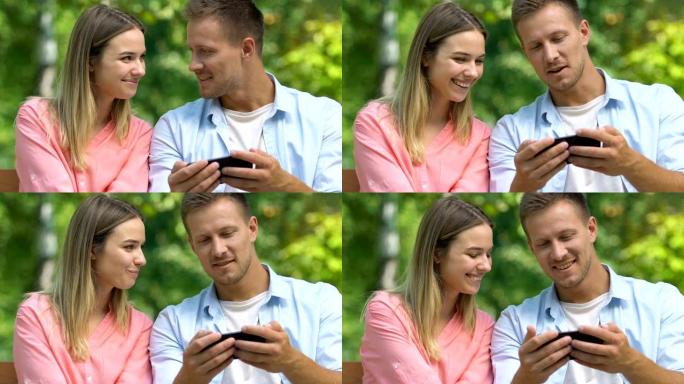 年轻人在公园的手机上展示女性恋爱视频游戏，同情
