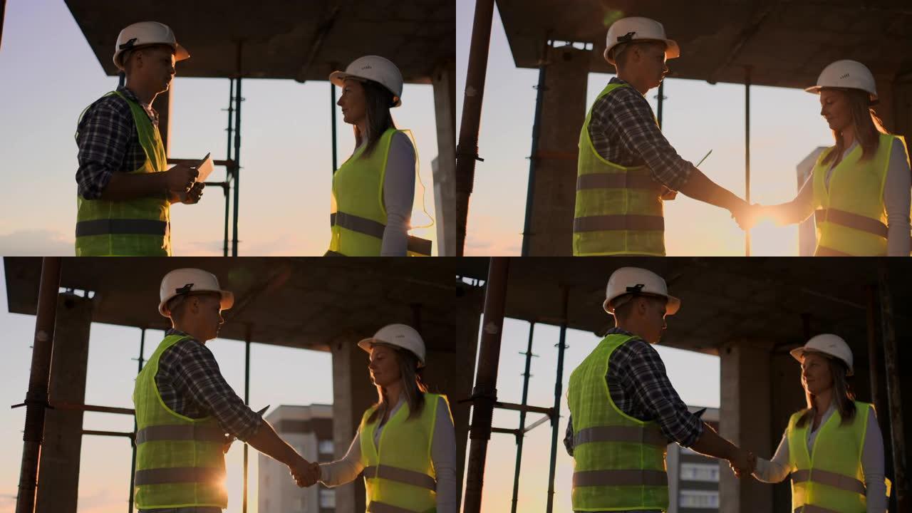 建筑，团队合作，伙伴关系，手势和人的概念-在施工现场握手的情况下，建筑工人们戴着手套互相问候。