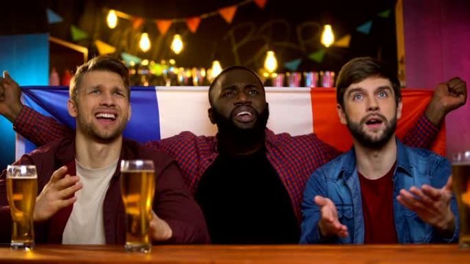焦虑的多种族法国球迷对球队输掉比赛感到不满，坐在酒吧里