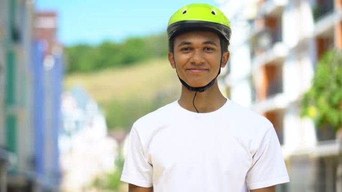 兴奋的非洲裔美国男性青少年戴着防护头盔微笑，骑自行车爱好