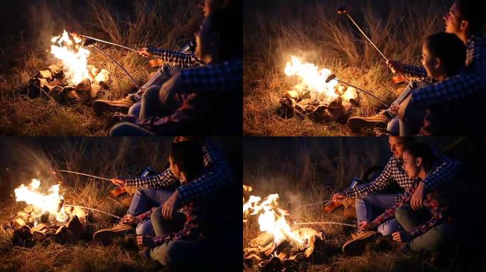 年轻夫妇在篝火上准备饭菜