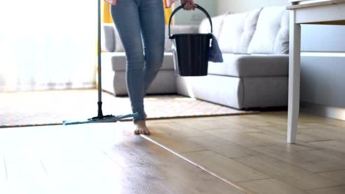 赤脚女孩用水桶和拖把走路，为房屋清洁服务做广告