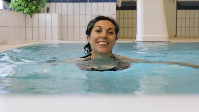 在健身房游泳池游泳的幸福女人的肖像