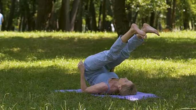 健康的生活方式，老妇人在公园的垫子上做瑜伽体式，业余锻炼