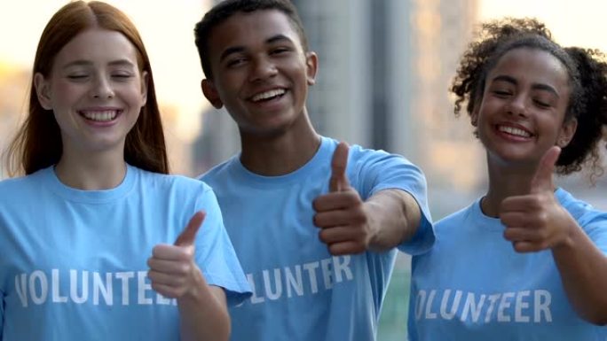 非常快乐的多种族志愿者朋友展示竖起大拇指的相机，慈善机构