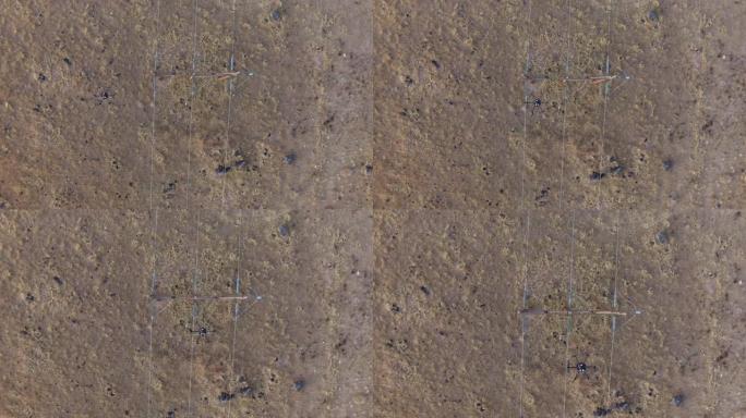 一架六架无人驾驶飞机在户外泥土和草地上方的电力线上空直接拍摄