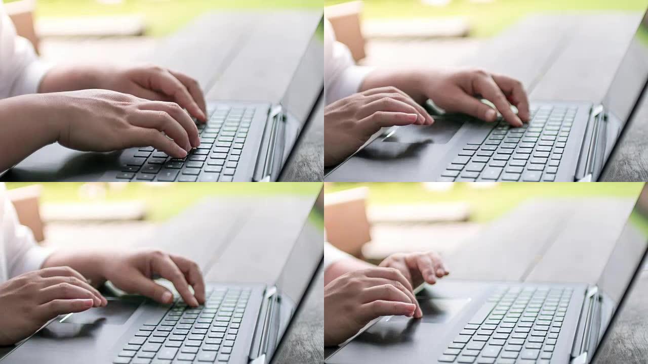女人手在户外笔记本电脑键盘上打字，背景为绿色，延时运动，缩小运动