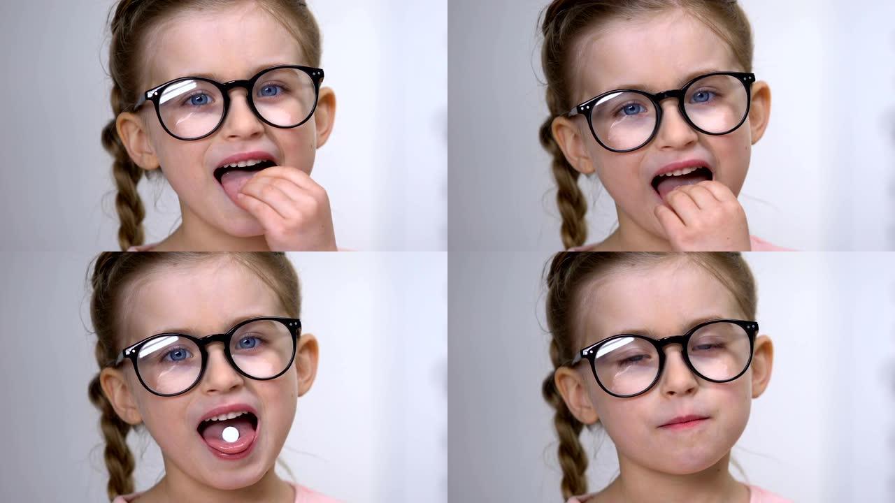 戴眼镜的小女孩服用白色药丸，视力维生素，健康补充剂