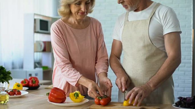 高级男人和充满爱心的妻子在厨房里烹饪健康的蔬菜午餐，家庭