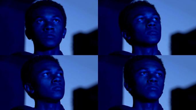 忧郁的非洲裔美国男性少年在蓝色的城市灯光，孤独的概念