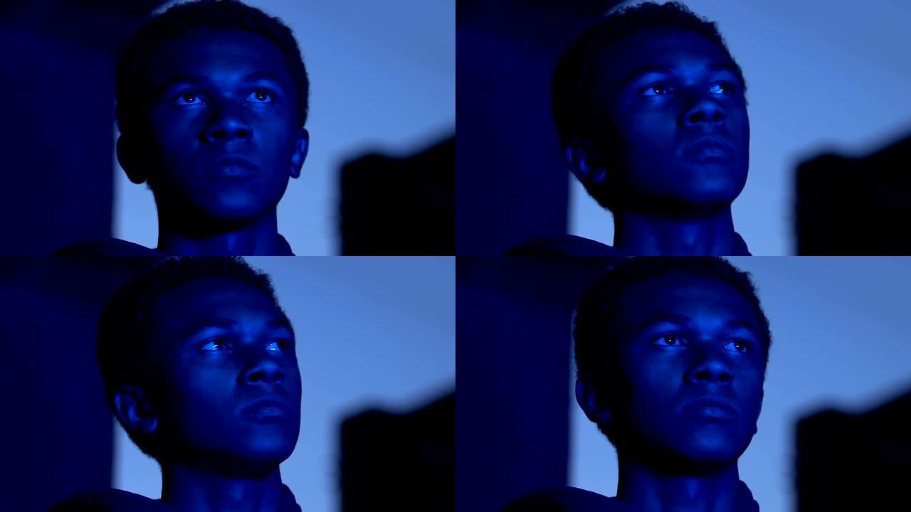 忧郁的非洲裔美国男性少年在蓝色的城市灯光，孤独的概念