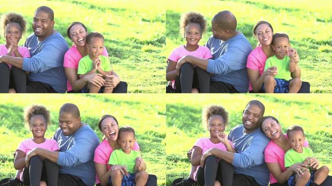 有两个孩子坐在草地上的快乐黑人家庭