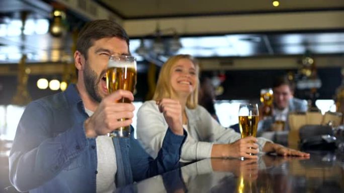 朋友在酒吧享受体育节目，为胜利而喝酒，啤酒传统