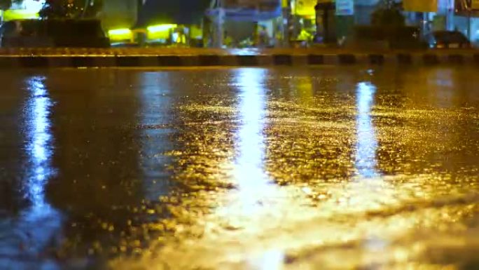 夜间有交通信号灯的雨水坑和掉落的水滴