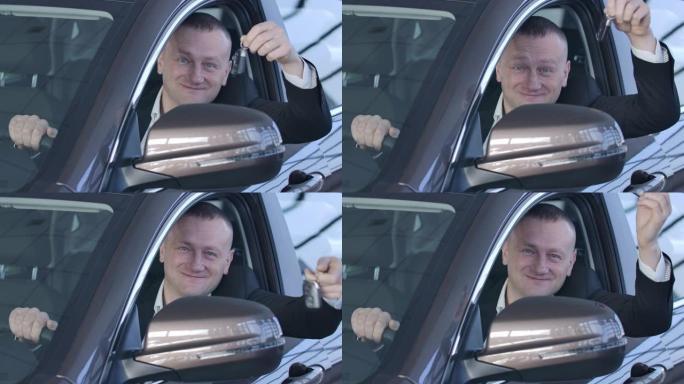 胖乎乎的白人男子在相机前吹嘘车钥匙并微笑的肖像。快乐的主人坐在车里，看着经销商的侧窗。陈列室，商业，
