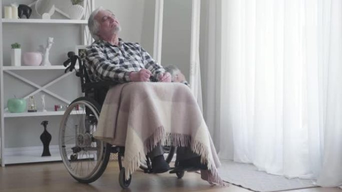 远射，紧张的老白人残疾人用拳头敲打着疼痛的膝盖。成年生病的退休老人坐在轮椅里。疾病，残疾，受伤，瘫痪