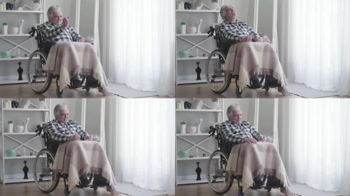 远射，紧张的老白人残疾人用拳头敲打着疼痛的膝盖。成年生病的退休老人坐在轮椅里。疾病，残疾，受伤，瘫痪