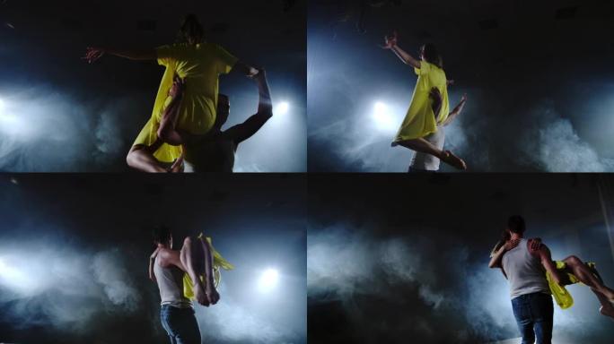 两个舞者一个男人和一个女人互相奔跑，一个男性伴侣举起一个穿着黄色连衣裙的女人，在空中旋转，表演顶级支