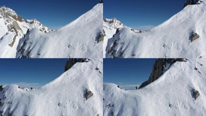 男性登山者登上陡峭的积雪覆盖的山脉的空中无人机视图