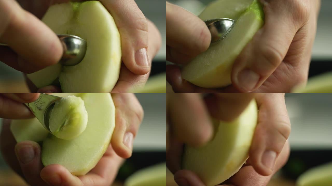 一个女人的手用小勺子将去皮和切成两半的苹果取芯的极端特写镜头