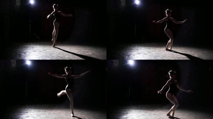 专业优雅灵活的芭蕾舞演员在工作室的黑色背景下，在她的尖头芭蕾舞鞋上跳舞。芭蕾舞演员展示了穿着芭蕾舞短