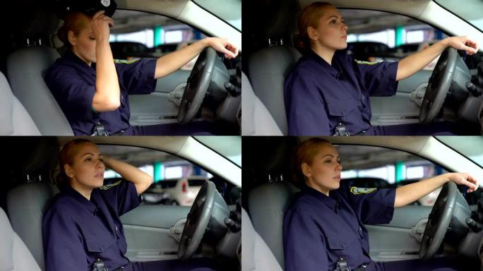 疲惫的女警脱下坐在巡逻车上的服务帽，夜班