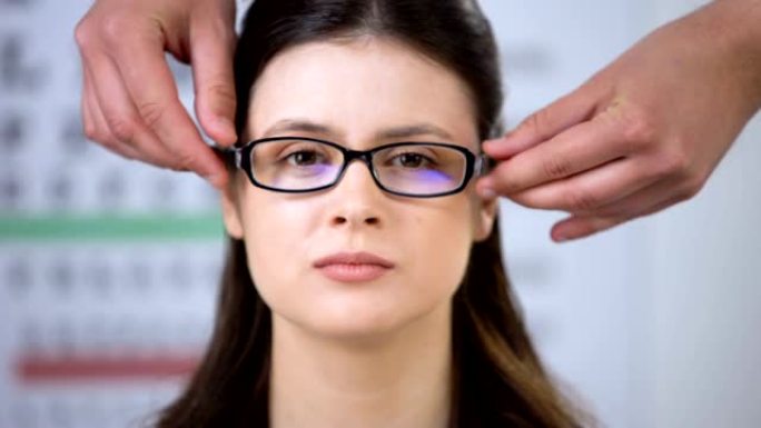 医生为视力模糊的女士戴上眼镜，病人聚焦视线