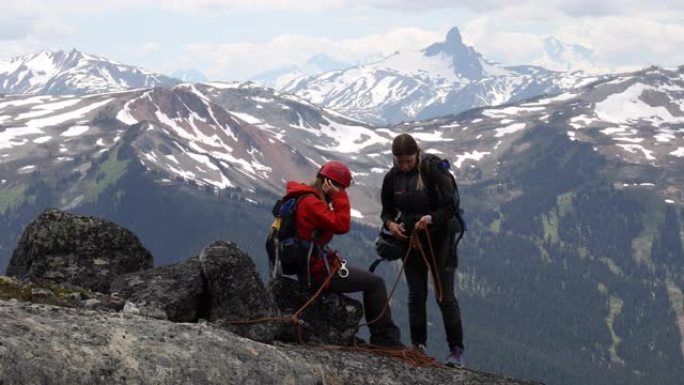 女攀岩者讨论路线，在岩石山顶上准备装备