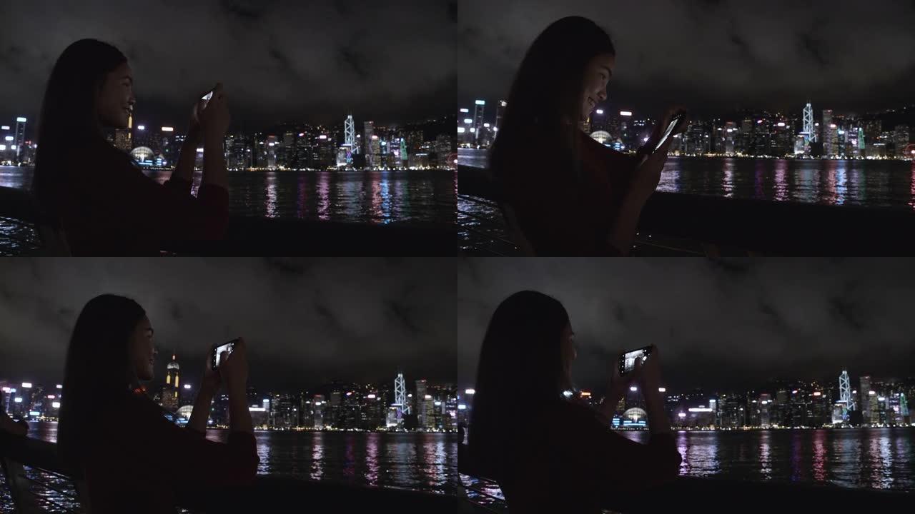 旅行者们用手机拍摄香港的夜景。