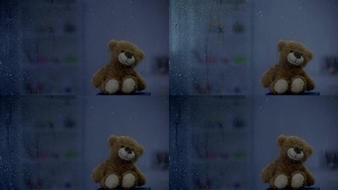 在雷雨天气下，在下雨的窗户后面的窗台上的泰迪熊，希望和支持