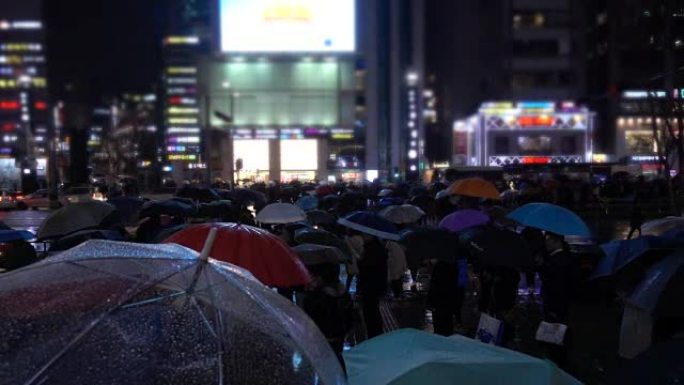 人们在不同灯光下的雨中行走在人行横道上，韩国首尔