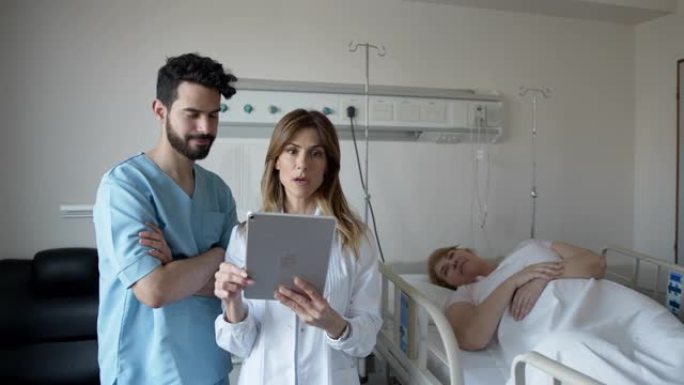 女医生在平板电脑上查看高级患者的病历时向男护士提供指导