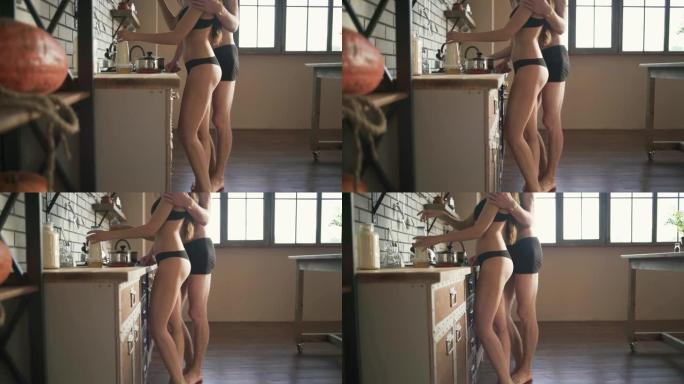 穿着内衣的女人站在厨房里。半裸身材完美的女孩做早餐或午餐。穿着内衣的女人屁股。